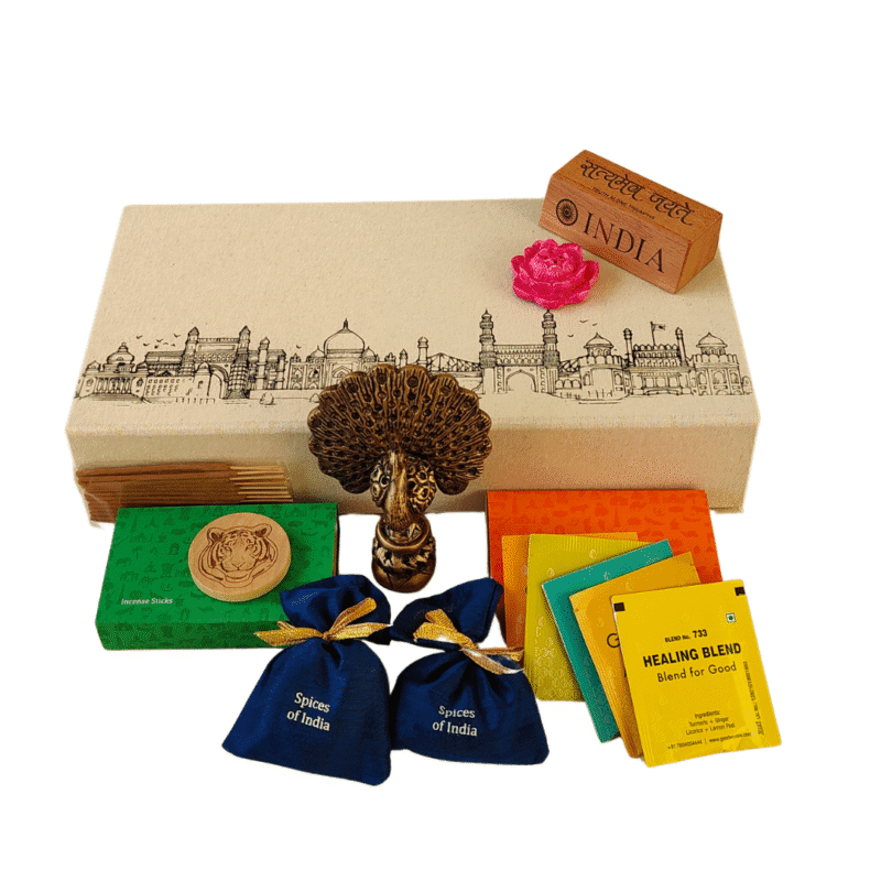 India-inspired souvenir gift hamper featuring handcrafted keepsakes, spice sachets, incense sticks, tea blends, a peacock figurine, and cultural memorabilia in decorative packaging.