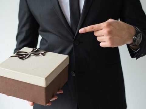 Corporate gifting etiquette at an international business event, a host presenting a gift box