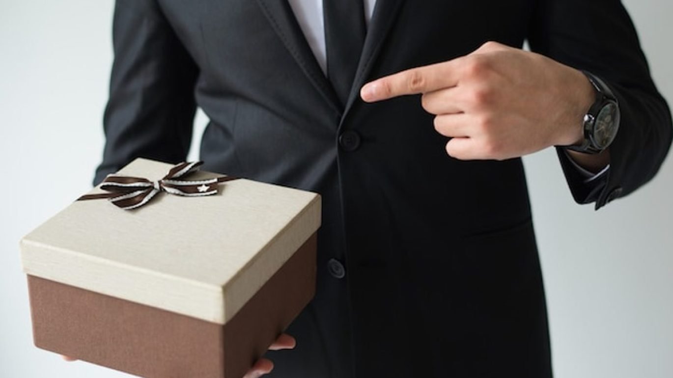 Corporate gifting etiquette at an international business event, a host presenting a gift box