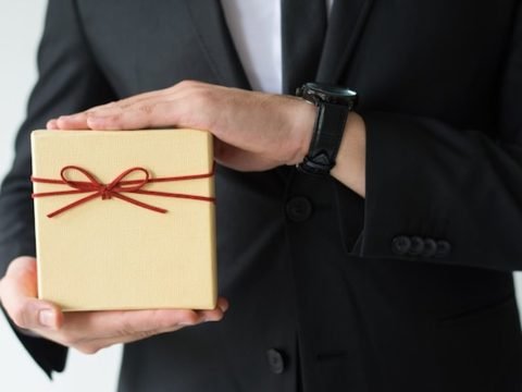 How to choose gifts for foreign delegates, a business host presenting a wrapped gift box