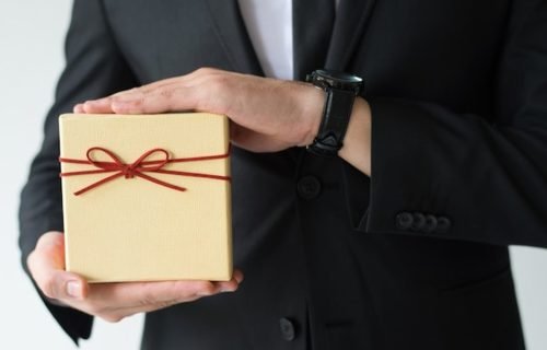 How to choose gifts for foreign delegates, a business host presenting a wrapped gift box