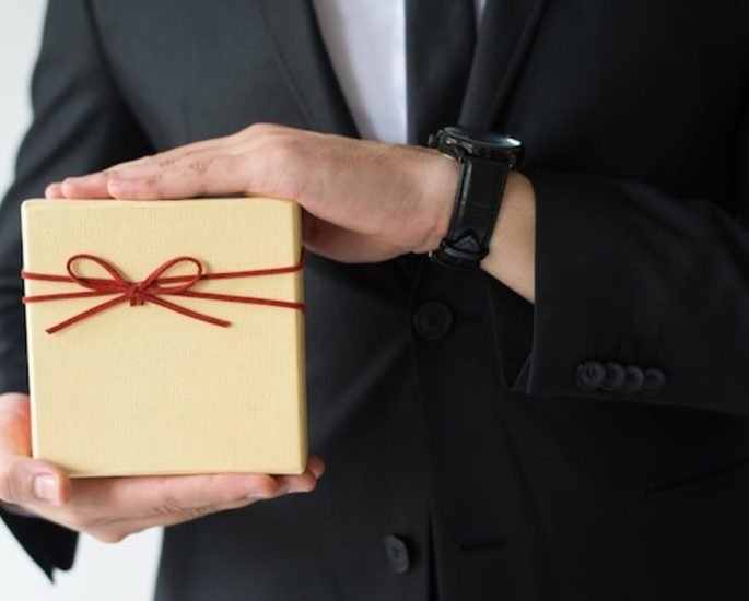 How to choose gifts for foreign delegates, a business host presenting a wrapped gift box