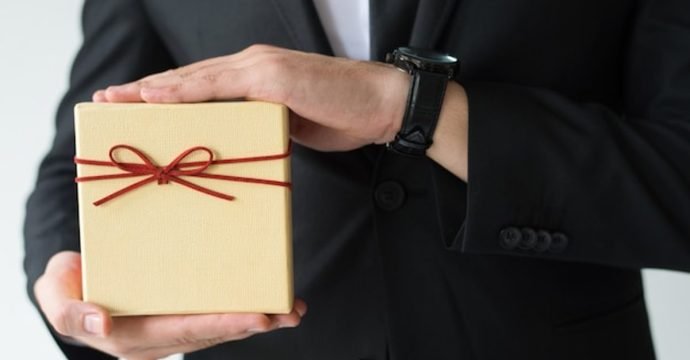 How to choose gifts for foreign delegates, a business host presenting a wrapped gift box